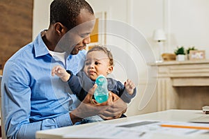 Happy father feeding his son and holding baby bottle