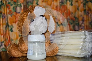 Baby bottle with fresh expresed milk, frozen breastmilk in storage bags and soft toy dog