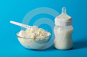 Baby bottle with milk for feeding. A plate with dry milk mixture with bifidobacteria, protein component and