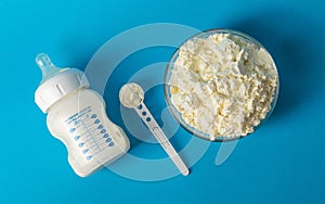 Baby bottle with milk for feeding. A plate with dry milk mixture with bifidobacteria, protein component and