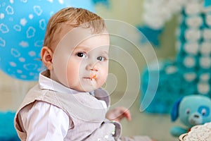 Baby boy 1 year in a photo Studio with a cake and balloons, Birthday of a child 1 year, baby eats cake