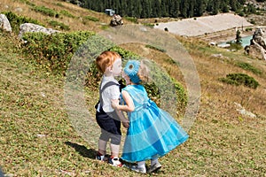 Baby boy and adorable child girl kissing on grass. Summer green nature