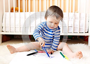 Baby boy age of 18 months paints with pens