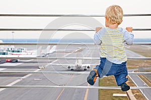 Baby boy in airport transit hall looking at airplane