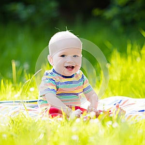 Baby boy with apple on family garden picnic