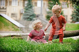 Baby boy and baby girl playing while sitting on green grass