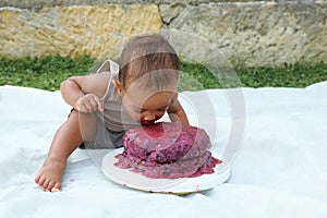 Baby boy biting first birthday cake
