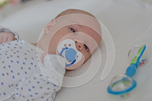 Baby boy with blue dummy lying