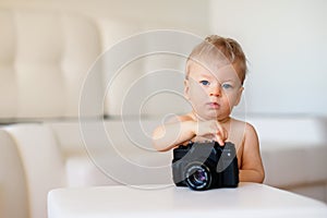 Baby boy with blue eyes. Toddler child exploring old camera