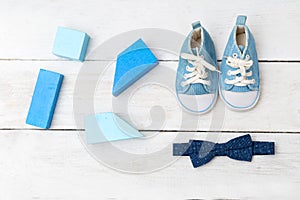 Baby boy blue shoes and blue wooden toys on wooden background. F