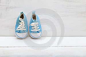 Baby boy blue sneakers on white wooden background