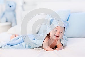 Baby boy in blue towel on white bed