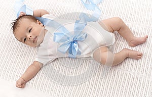 Baby boy in bodysuit and blue ribbon