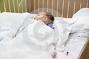 Baby boy with breathing tube in nose receiving medical treatment. Intensive care and attaching intravenous tube to hand on bed