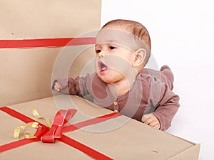 Baby boy in brown clothes singing Christmas carols by gift