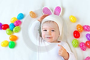 Baby boy in bunny hat lying on green blanket with