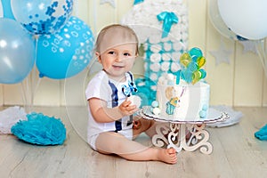 Baby boy celebrates 1 year with cake and balloons, happy childhood, children`s birthday