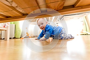 Baby boy crawling on floor and looking under the bed