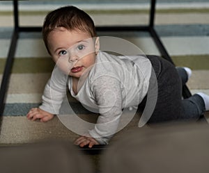 Baby boy crawling under a coffee table