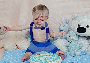 Baby boy crying while eating his birthday party cake