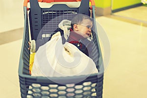 Baby boy crying in a supermarket in a cart. The Forgotten Child. toned