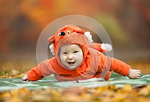 Baby boy dressed in fox costume in autumn park
