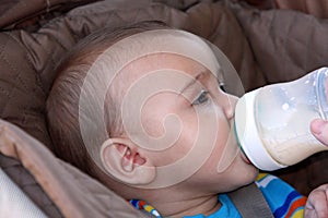 Baby boy drinking bottle in stroller