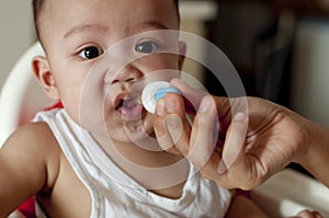 A baby boy is drinking his vitamins using a dropper