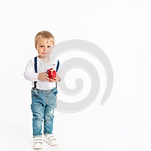 Baby boy eating apple and smiling in the studio isolated on white background