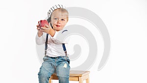 Baby boy eating apple and smiling in the studio isolated on white background