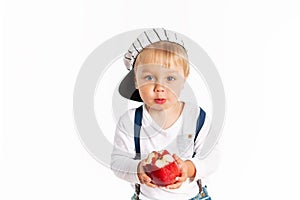 Baby boy eating apple and smiling in the studio isolated on white background