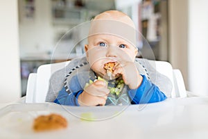 Baby boy eating with BLW method, baby led weaning