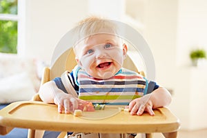 Baby Boy Eating Fruit In High Chair