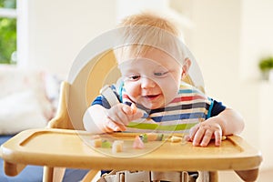 Baby Boy Eating Fruit In High Chair