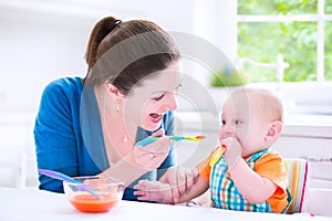 Baby boy eating his first solid food with his mother