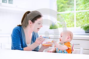 Baby boy eating his first solid food witn his mother