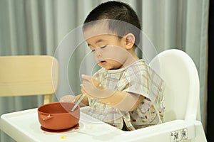 Baby boy eating with silver spoon by himself