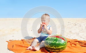 Baby boy eating watermelon slice against beach background