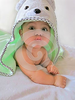 Baby boy with funny surprised face wearing bear-head pool-towel is on a white background