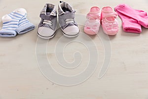Baby boy and girl shoes and socks on wooden background