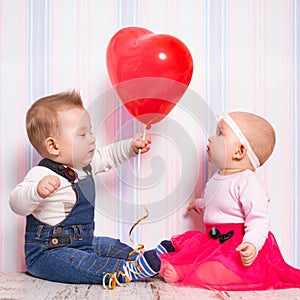 Baby boy giving a heart balloon to the girl