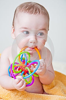 Baby Boy Gnawing Multicolored Toy on Yellow Towel photo