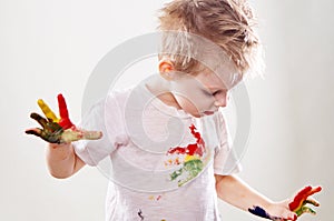 The baby boy with gouache soiled hands and shirt isolated