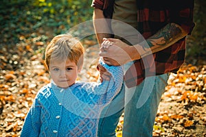 Baby boy has a good time and walk holding father's tattooed strong hand. Happy dad and son spending time together