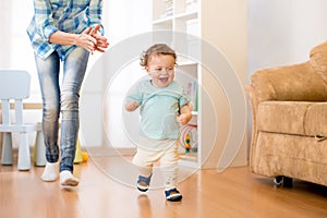 Baby boy have a fun running in living room with his mother