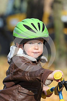 Baby boy in helmet learning to ride on bike