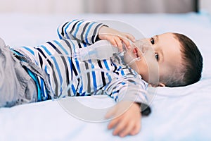 Baby boy holding a mask immobilizer sprayer while taking a breath