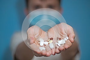 baby boy holds on palms of capsule and white tablets. teenager in protective medical mask stretches drugs forward. hild with flu,