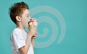 Baby boy kid eat raspberry and vanilla ice-cream in waffles cone on blue mint