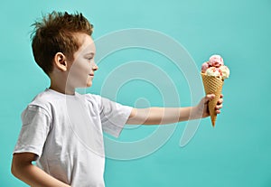 Baby boy kid eat raspberry and vanilla ice-cream in waffles cone on blue mint